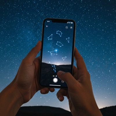Person using a smartphone stargazing app to identify constellations at night