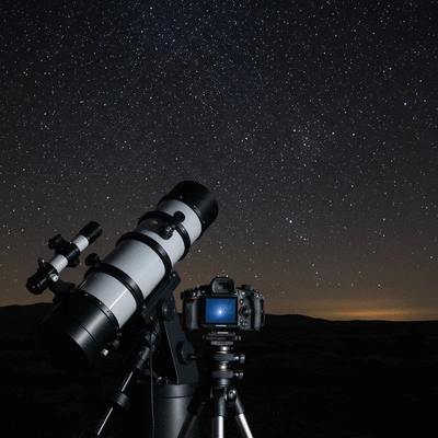 Astrophotography setup with telescope and camera under a starry night sky